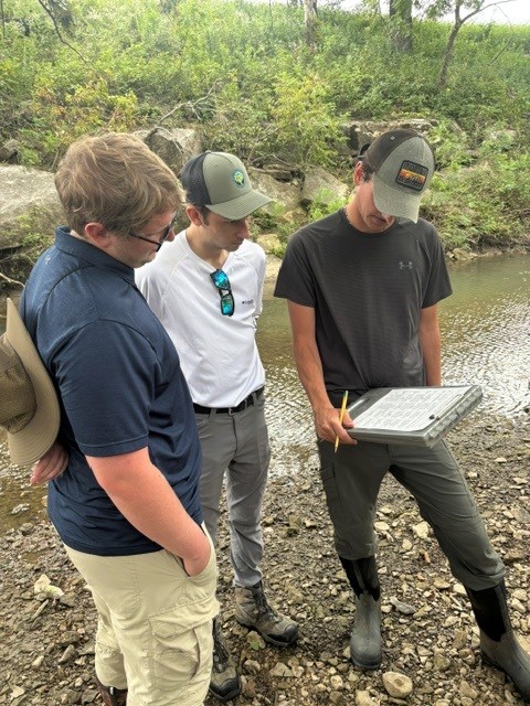 Field staff reviewing watershed information beside a stream